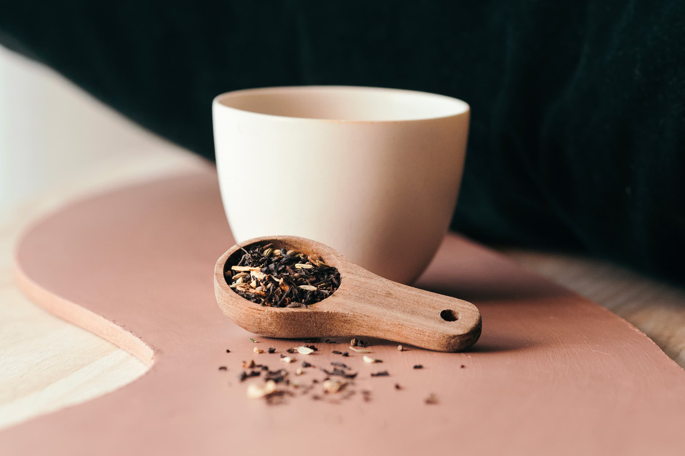 thé en vrac dans une cuillère en bois avec une tasse blanche